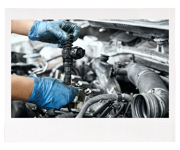 Technician holding used fuel injector over engine
