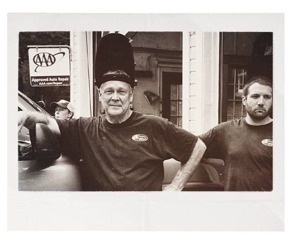 black and white photo of two men standing in front of an auto repair shop