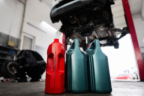transmission fluid containers sitting on the floor in front of a vehicle on a service lift.